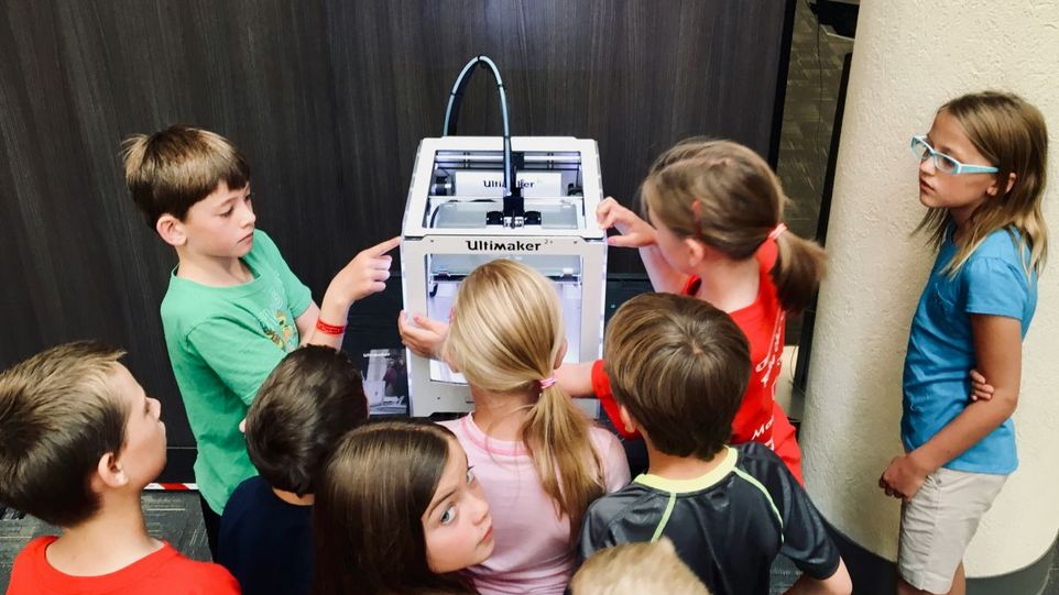 Schulkinder stehen um einen Drucker herum